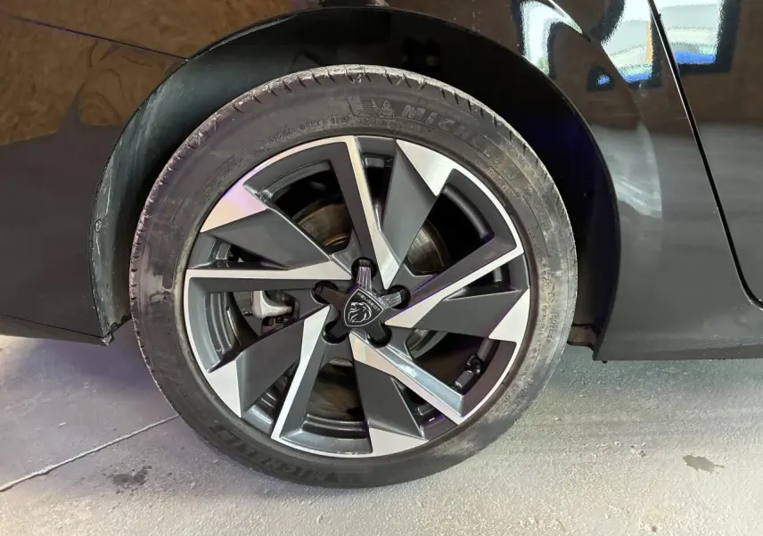 Gros plan sur la jante alliage 17'' Halong diamantée noire et argentée d’une Peugeot 308 SW noire, côté arrière droit.