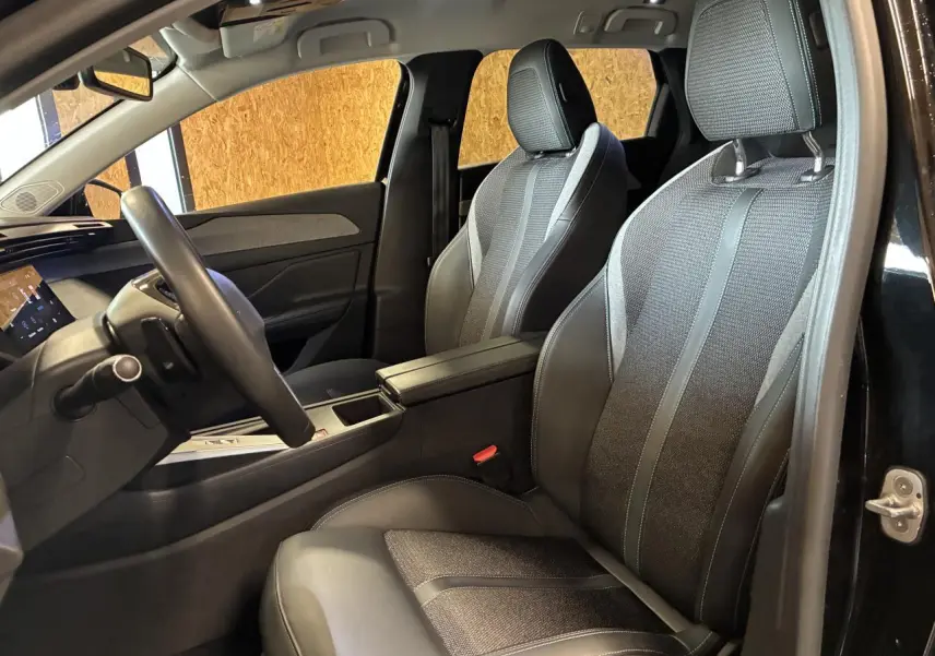 Intérieur avant droit de la Peugeot 308 SW 2024 noire, sièges bi-matière TEP/tissu avec accoudoir central.