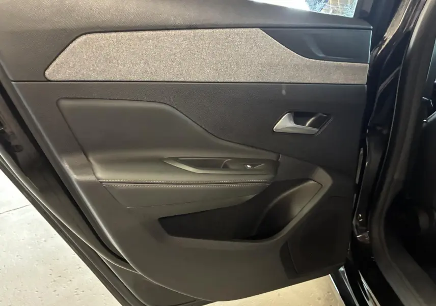 Porte arrière gauche ouverte d’une Peugeot 308 SW noire, montrant le panneau intérieur avec garniture textile et plastique noir.