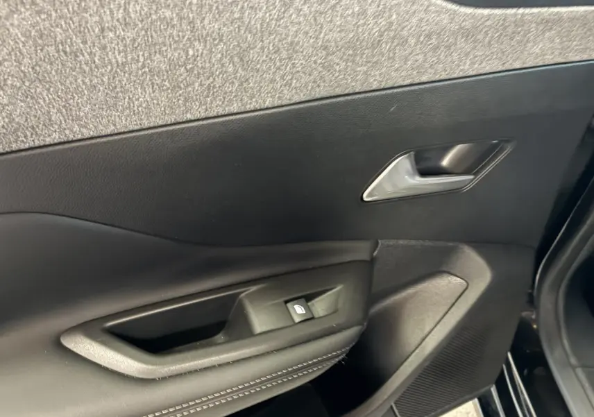 Gros plan sur la porte avant gauche noire du Peugeot 308 SW 2024 avec poignée et commande de vitre électrique.