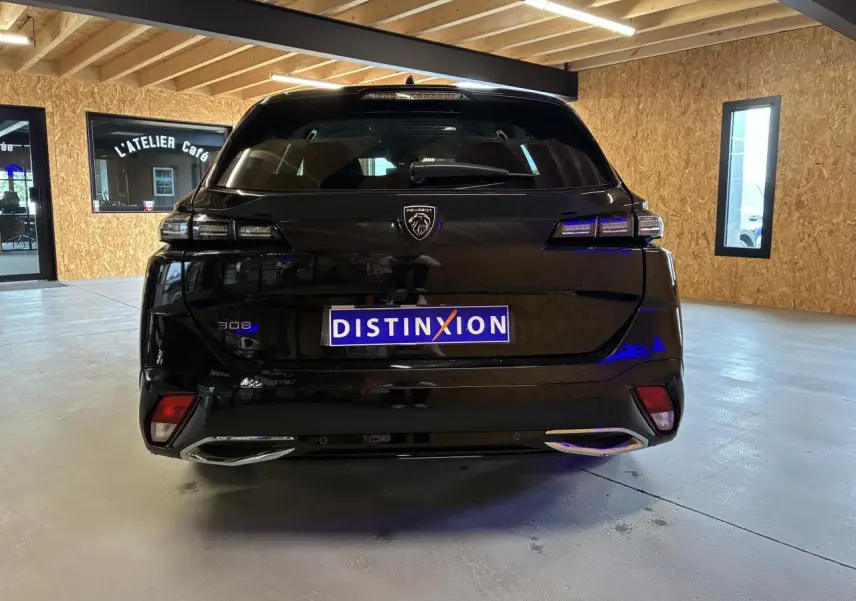 Vue arrière d'un Peugeot 308 SW noir brillant avec feux LED et double sortie d'échappement chromée en intérieur.