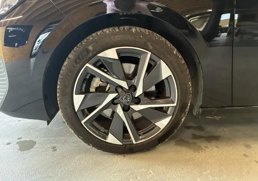 Gros plan sur la roue avant gauche noire avec jante alliage 17'' Halong diamantée du Peugeot 308 SW 2024.