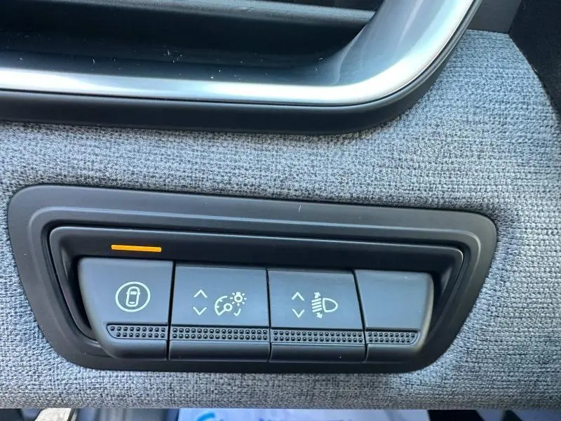 Gros plan sur les commandes de réglage de luminosité et phares sur tissu gris à l'intérieur d'une Renault Clio 2025.