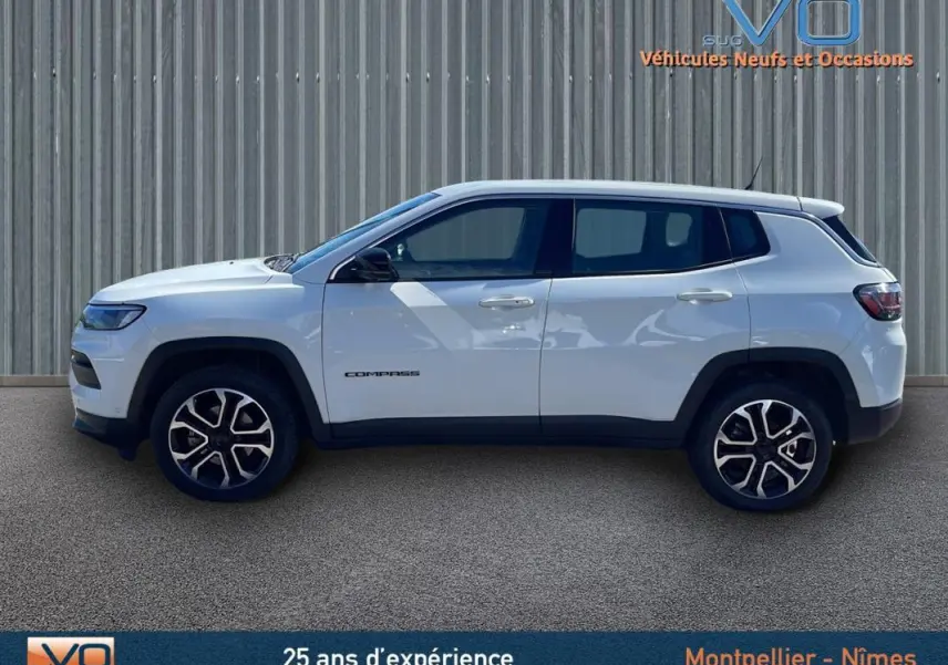 Profil côté gauche du Jeep Compass blanc 2024 avec jantes alliage 18 pouces et logo visible sur la porte.