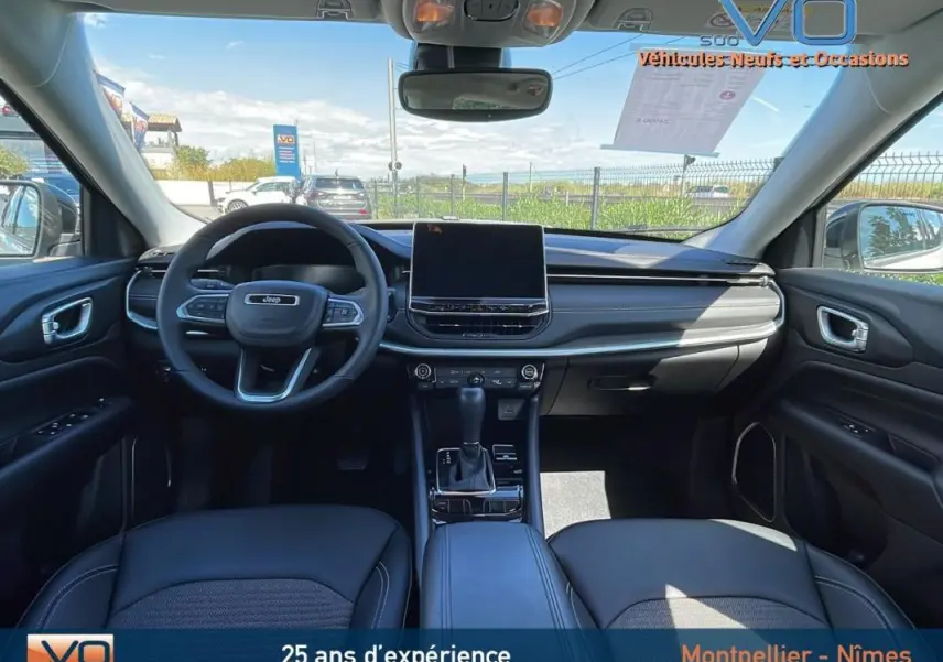 Vue intérieure avant du Jeep Compass 2024 avec tableau de bord moderne, écran tactile et volant multifonction noir.