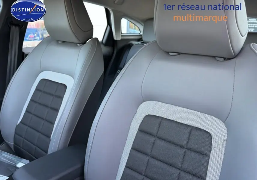 Gros plan sur les sièges avant gris clair et noir de la Citroën C4 électrique 2025 avec accoudoir central.