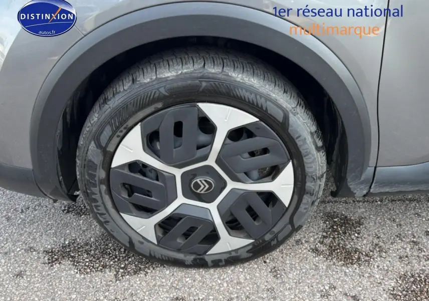 Gros plan sur la roue avant droite d'une Citroën C4 électrique 2025 gris foncé avec jante au design moderne.