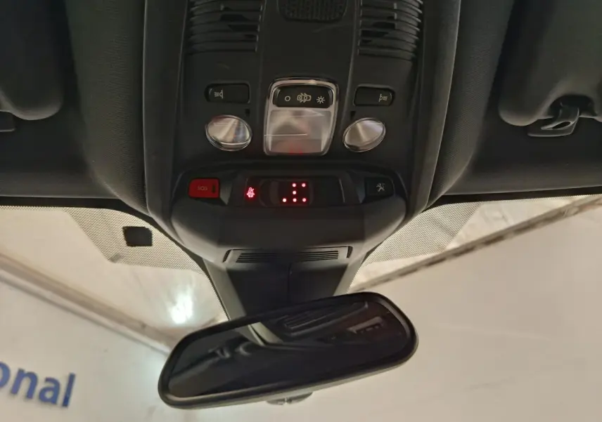 Vue intérieure du plafonnier et du rétroviseur central du Peugeot 5008 gris clair, avec commandes et voyants lumineux rouges.