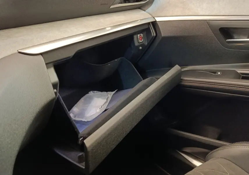 Intérieur côté passager du Peugeot 5008 gris clair, boîte à gants ouverte avec rangement visible.