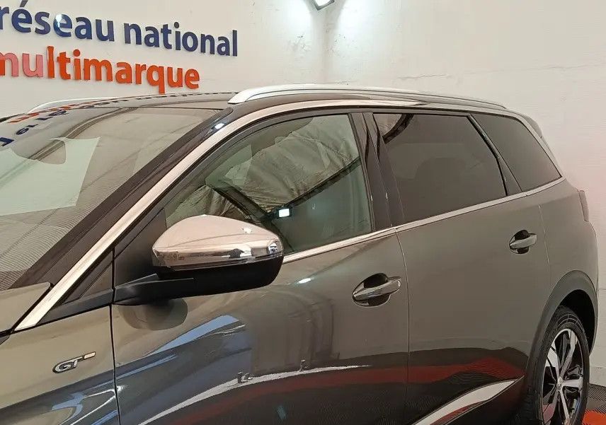 Vue latérale droite d’un Peugeot 5008 GT gris clair avec rétroviseur chromé et jantes distinctives.