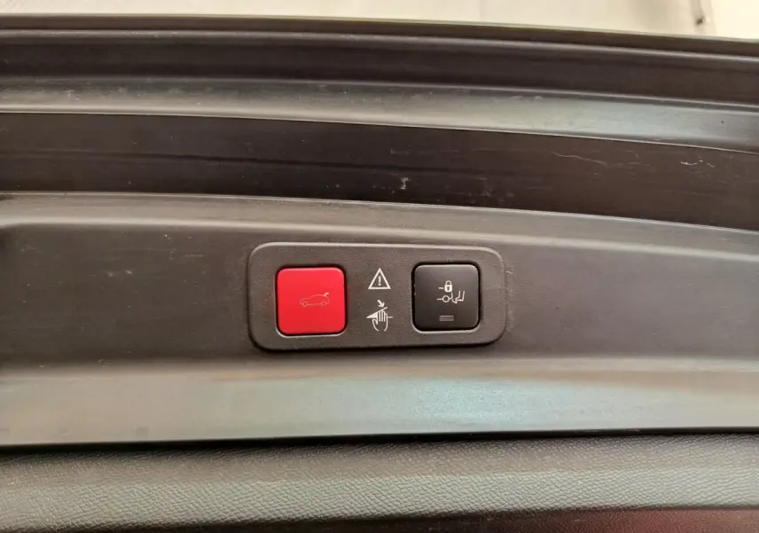 Gros plan sur les boutons de commande du coffre électrique, intérieur noir du Peugeot 5008 gris clair.