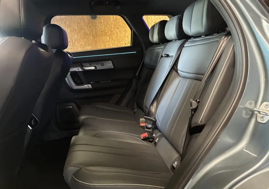 Vue intérieure côté droit des sièges arrière en cuir noir du SUV JAECOO J7 2026, avec ceinture de sécurité et éclairage d'ambiance.