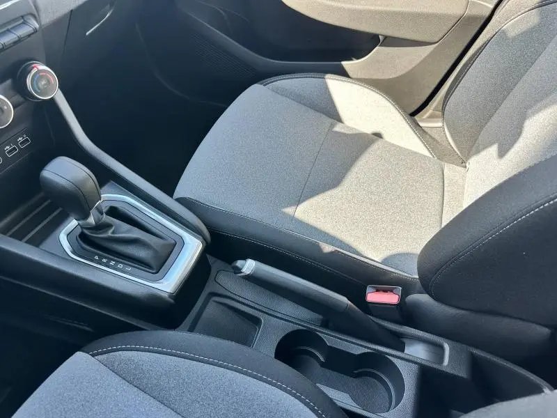 Vue intérieure côté droit montrant la console centrale avec levier de vitesse et sièges en textile gris motif 3D.