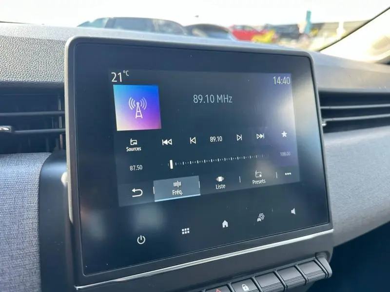Écran tactile central affichant la radio FM dans l'habitacle gris d'une Renault Clio 2025, vue de face.