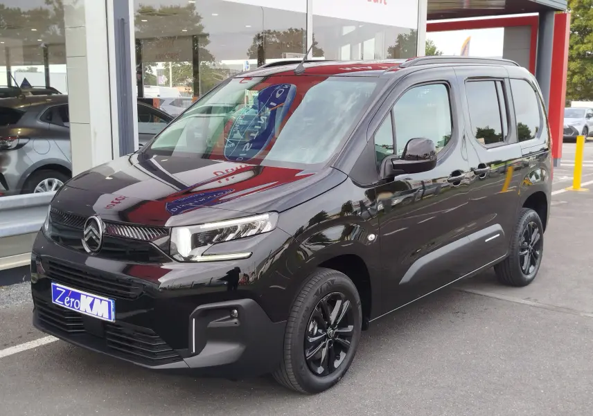 Vue 3/4 avant droite d'un Citroën Berlingo noir Perla Nera métallisé avec jantes noires et calandre distinctive.