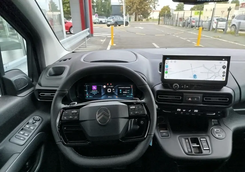 Intérieur du Citroën Berlingo 2025 noir, vue frontale du poste de conduite avec volant multifonction et écran tactile GPS.