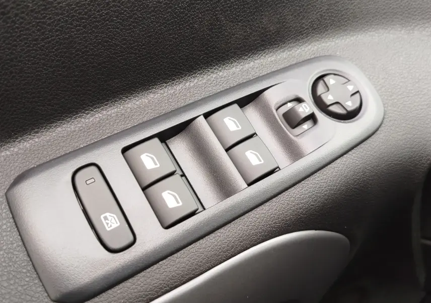 Gros plan sur les commandes électriques des vitres et rétroviseurs côté gauche d'un Citroën Berlingo noir Perla Nera 2025.