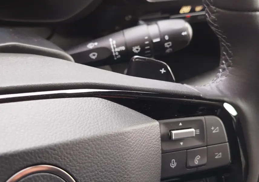 Gros plan sur les commandes du volant en cuir noir du Citroën Berlingo 2025, avec boutons multifonctions et palettes au volant.