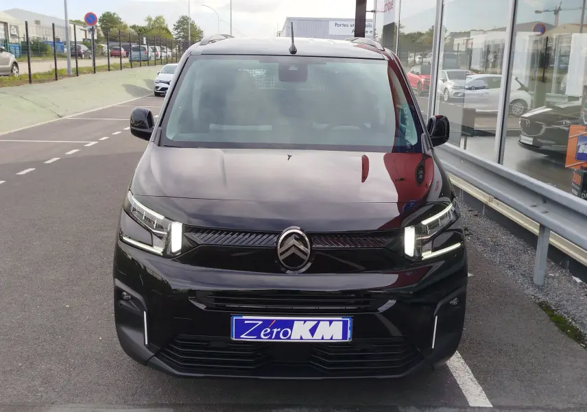 Vue avant d'un Citroën Berlingo noir Perla Nera avec feux LED allumés sur un parking extérieur.