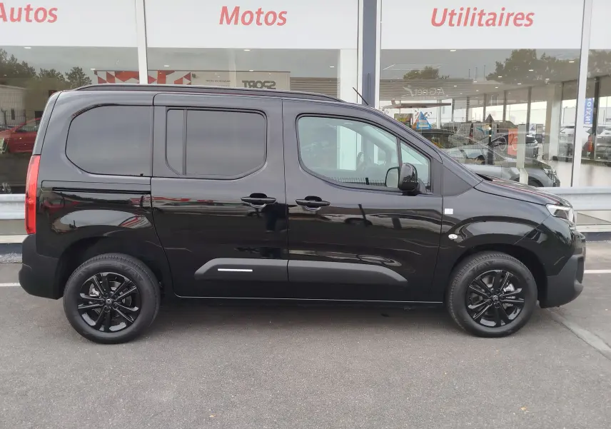 Profil droit d'un Citroën Berlingo noir Perla Nera 2025 avec jantes noires et vitres teintées, stationné devant un showroom.