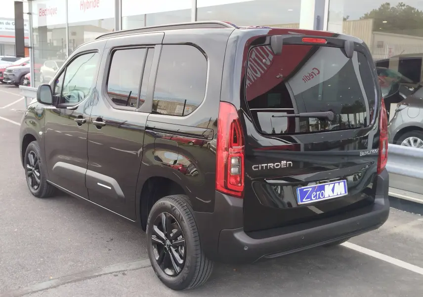 Vue 3/4 arrière droite d'un Citroën Berlingo noir Perla Nera métallisé avec vitres teintées et jantes noires.