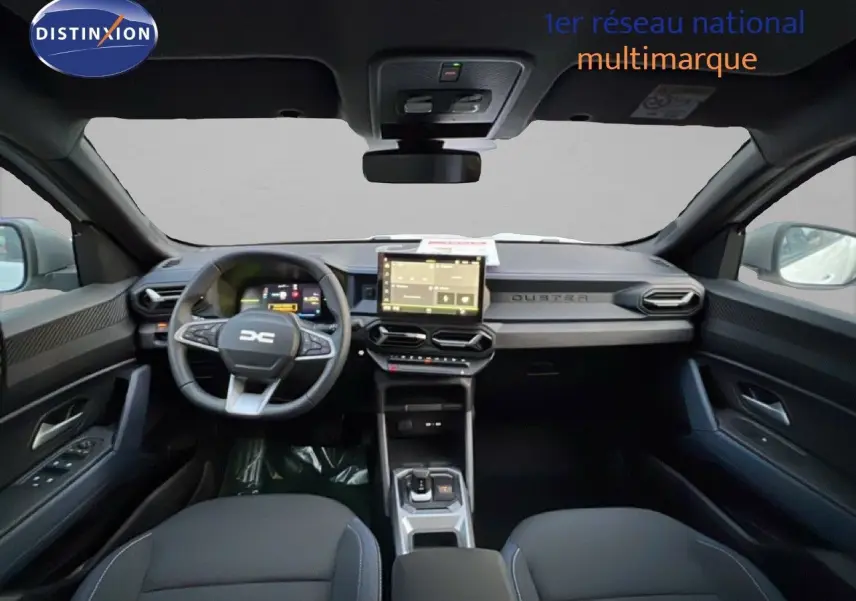 Vue intérieure avant du Dacia Duster 2025, tableau de bord noir avec écran tactile central et volant multifonction.