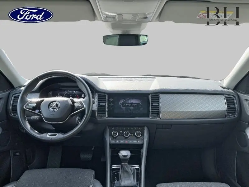 Vue intérieure frontale du tableau de bord et volant cuir noir du Skoda Kodiaq 1.5 TSI 2023 avec écran tactile central.