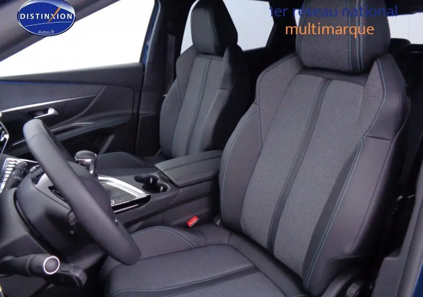 Vue intérieure côté conducteur du Peugeot 3008 2023, sièges tissu et cuir noir avec surpiqûres bleues et console centrale.