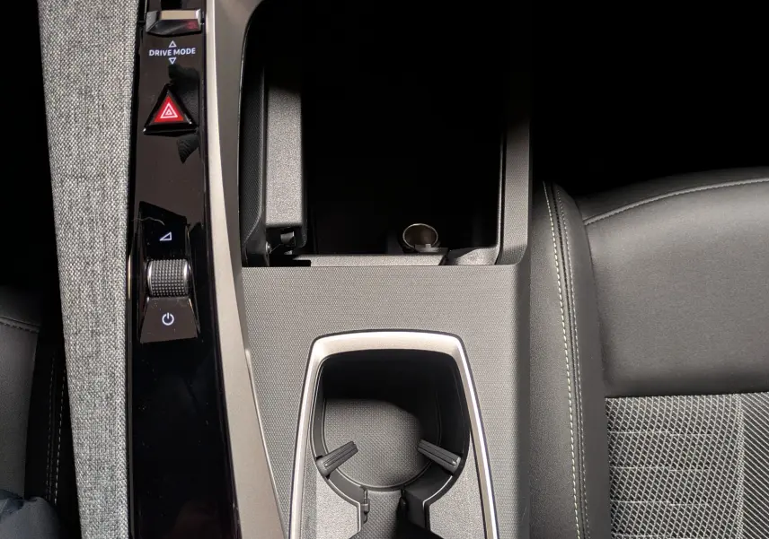 Vue plongeante sur la console centrale noire du Peugeot 3008 Hybrid 145 GT avec porte-gobelets et commandes tactiles.