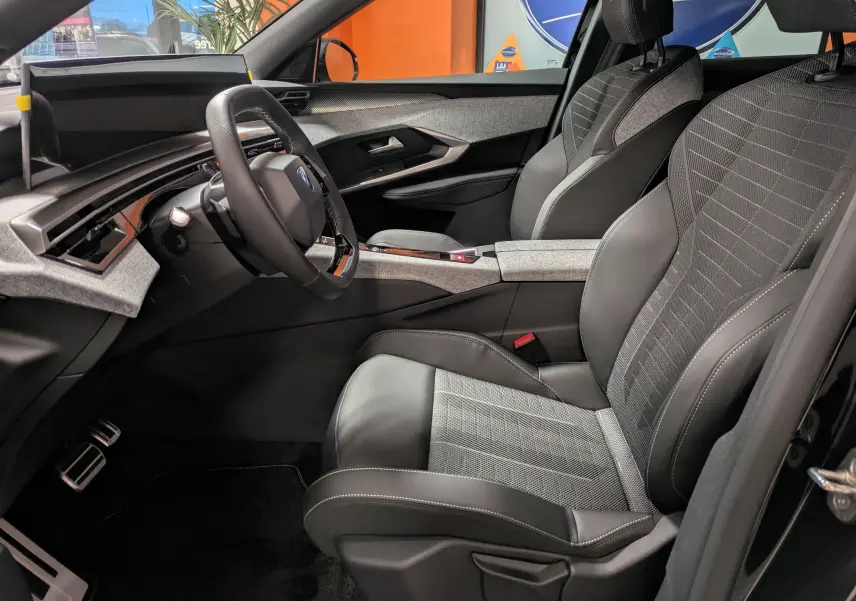 Vue intérieure côté conducteur du Peugeot 3008 Hybrid 145 GT 2025, sièges tissu/teppé gris avec surpiqûres Iced Clay.