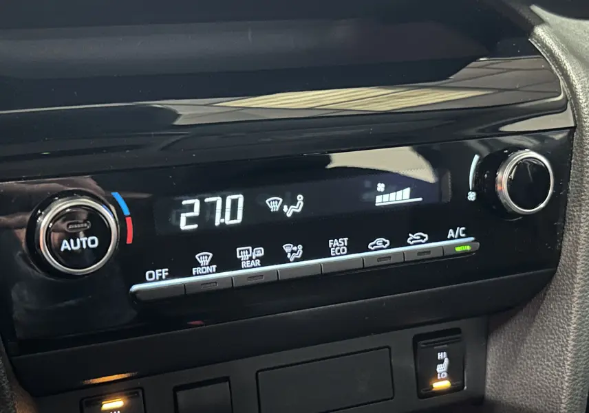 Détail de la console de climatisation digitale de la Toyota Yaris Cross 2025 gris minéral, avec réglage à 27°C et sièges chauffants activés.