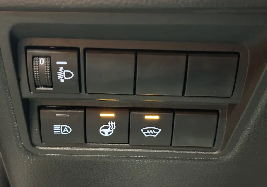 Gros plan sur les boutons de commande du volant et pare-brise chauffants dans une Toyota Yaris Cross gris minéral.