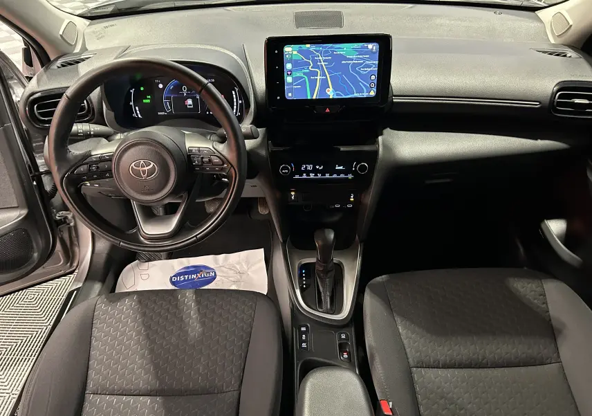 Vue intérieure frontale du tableau de bord et volant noir de la Toyota Yaris Cross 116h avec écran tactile et sièges tissu gris.