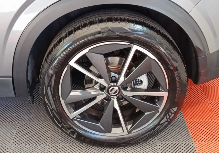 Gros plan sur la roue avant droite du Nissan Qashqai gris foncé, mettant en valeur la jante alliage au design moderne.