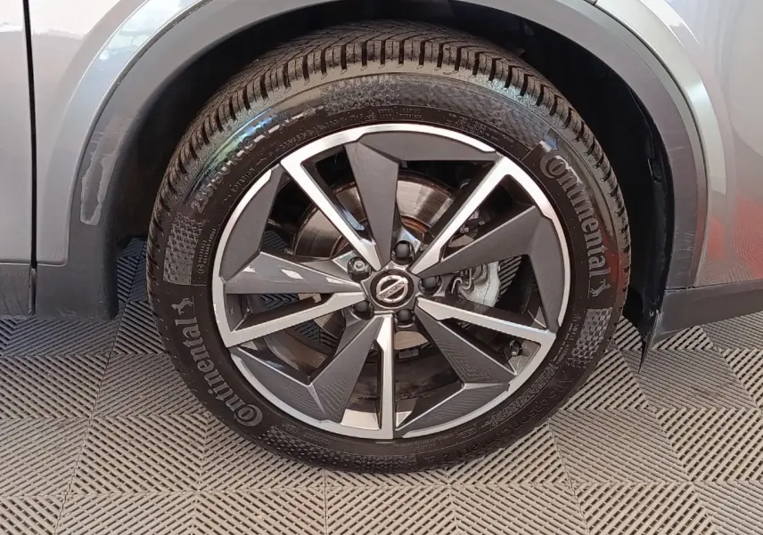 Gros plan sur la roue avant gauche du Nissan Qashqai gris foncé, avec jante alliage bicolore et pneu Continental.