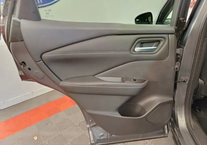 Vue intérieure de la porte arrière gauche gris foncé du Nissan Qashqai 1.3 MHEV 2022 avec accoudoir et commande de vitre.