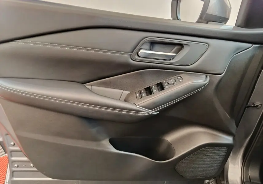 Vue rapprochée de la porte avant gauche du Nissan Qashqai gris foncé avec commandes électriques et garniture cuir.
