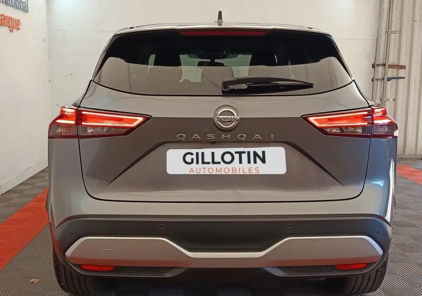 Vue arrière d'un Nissan Qashqai gris foncé 2022 avec feux LED allumés dans un showroom.