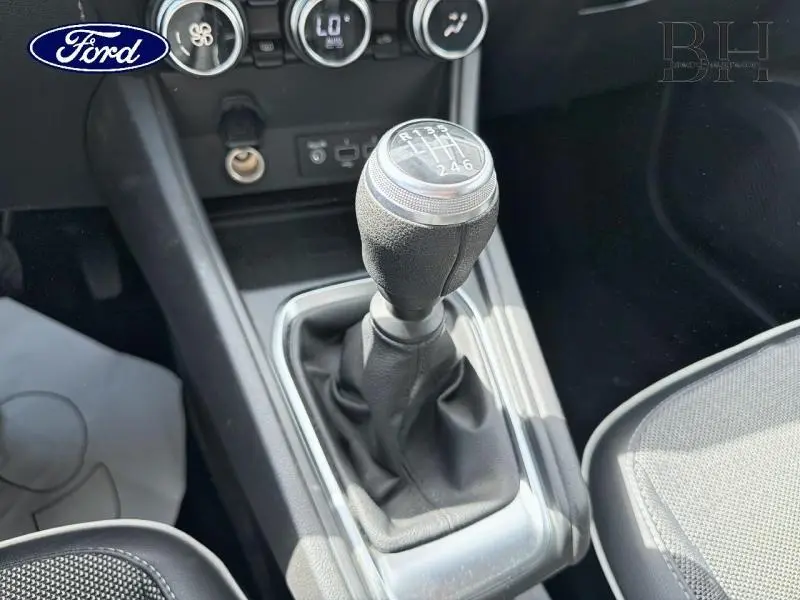 Levier de vitesse manuel en cuir vu de dessus dans l'habitacle d'un Renault Captur Gris Cassiopée, détails du tableau de bord visibles.
