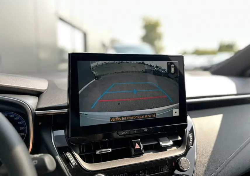 Écran multimédia affichant la caméra de recul dans l’habitacle d’une Toyota Corolla Touring Sport blanche.