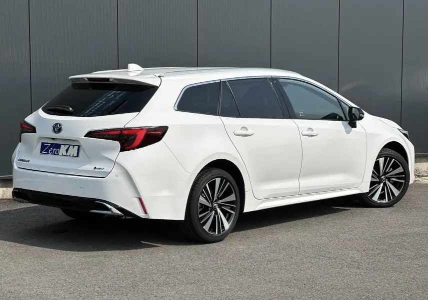 Toyota Corolla Touring Sport blanc Neige vue 3/4 arrière droit avec jantes alliage et vitres surteintées.