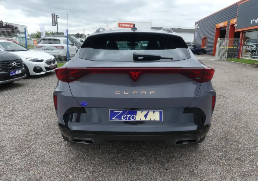 Vue arrière d'une CUPRA Formentor gris Graphene avec logo rouge et double sortie d'échappement noire sur parking.