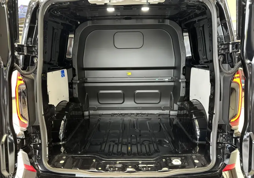 Vue arrière ouverte du Volkswagen Transporter T7 ProCab noir Minuit, montrant l'espace de chargement vide et les feux arrière LED allumés.