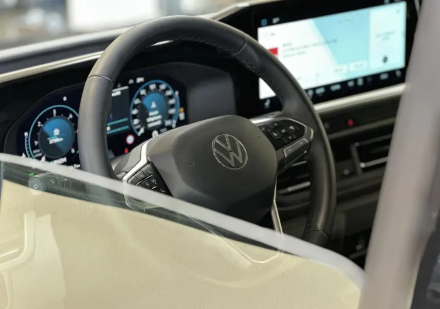 Vue intérieure centrée sur le volant multifonction noir et l'écran tactile large du Volkswagen Transporter T7.