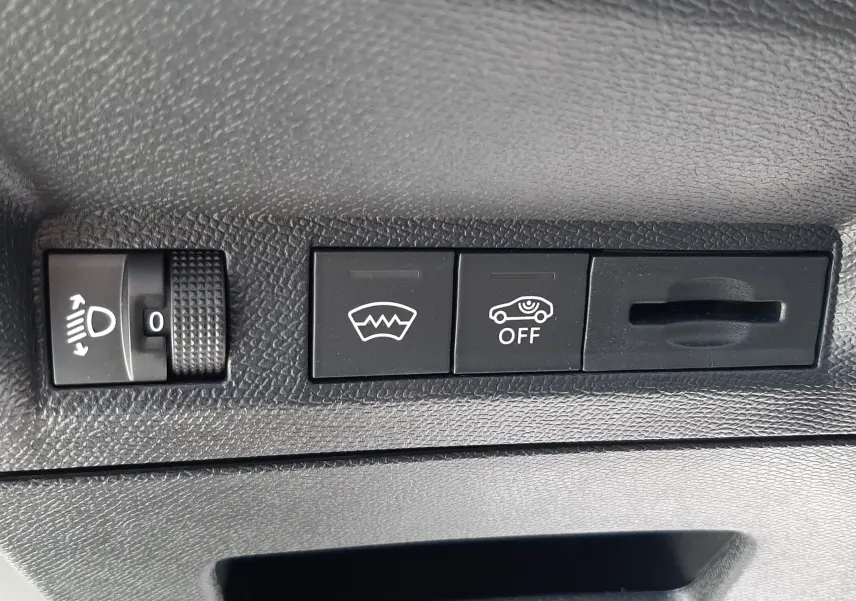 Détail des commandes intérieures noires avec réglage des phares et boutons de désembuage et assistance sur Peugeot 3008 blanc.