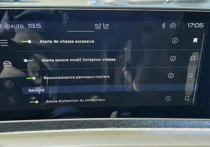 Écran tactile intérieur du Peugeot 3008 Hybrid 2024 affichant les alertes de sécurité, avec reflet extérieur flou.