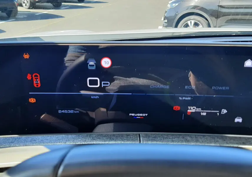 Vue intérieure du tableau de bord numérique du Peugeot 3008 blanc, affichant la vitesse à 0 km/h et les alertes de sécurité.