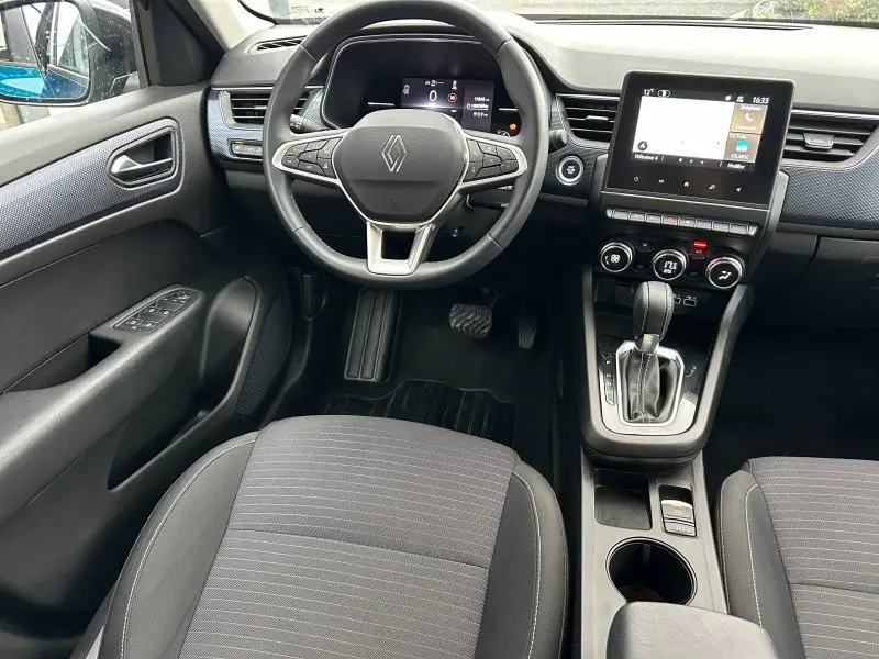 Vue intérieure avant du Renault Arkana 2025, tableau de bord avec écran tactile, volant multifonction et levier de boîte automatique.