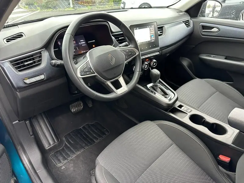 Vue intérieure côté conducteur du Renault Arkana 2025 bleu Zanzibar, avec volant multifonctions et console centrale équipée d’un écran tactile.