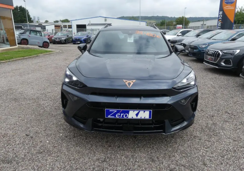 Vue frontale d'un CUPRA Formentor gris Graphene avec logo cuivré et phares LED allumés sur un parking.